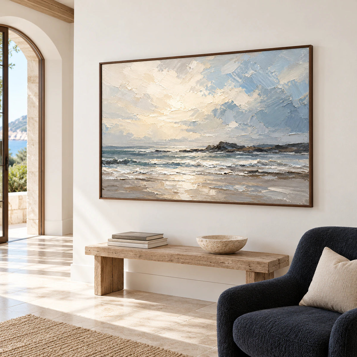 Large seascape painting in a bright foyer with a high ceiling, pale stone floor and tall architectural opening, viewed from a left approach.