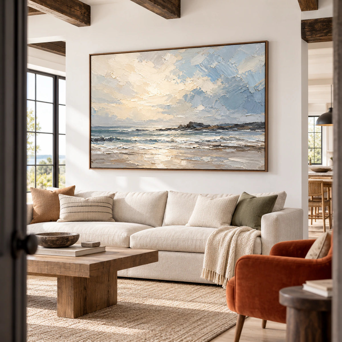 Large seascape painting in an expansive hospitality loft with generous windows, exposed dark beams and pale linen seating, viewed from a distant, slightly low right angle.