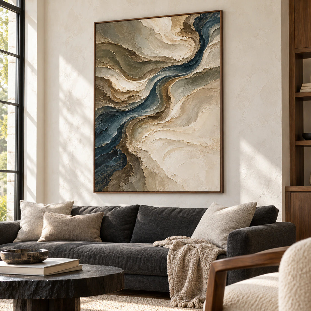 Prominent vertical abstract artwork above a charcoal sofa in a bright living room with pale walls and daylight.