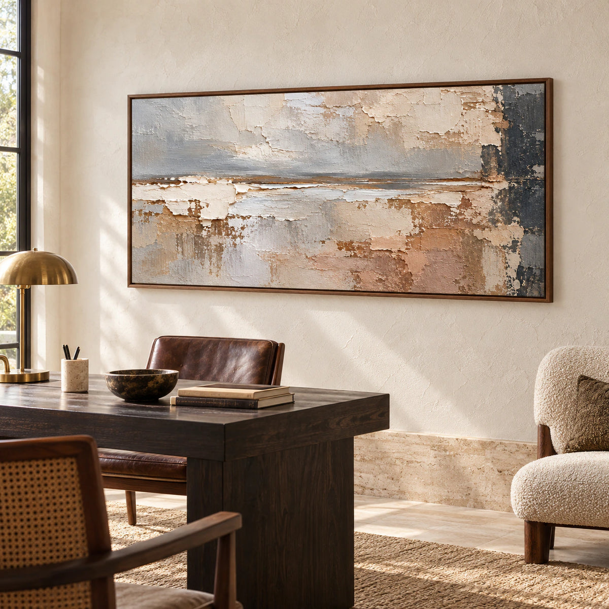 Horizontal abstract painting on a light wall beside a dark desk and simple reading chair in an airy home office, viewed from a slight left angle.