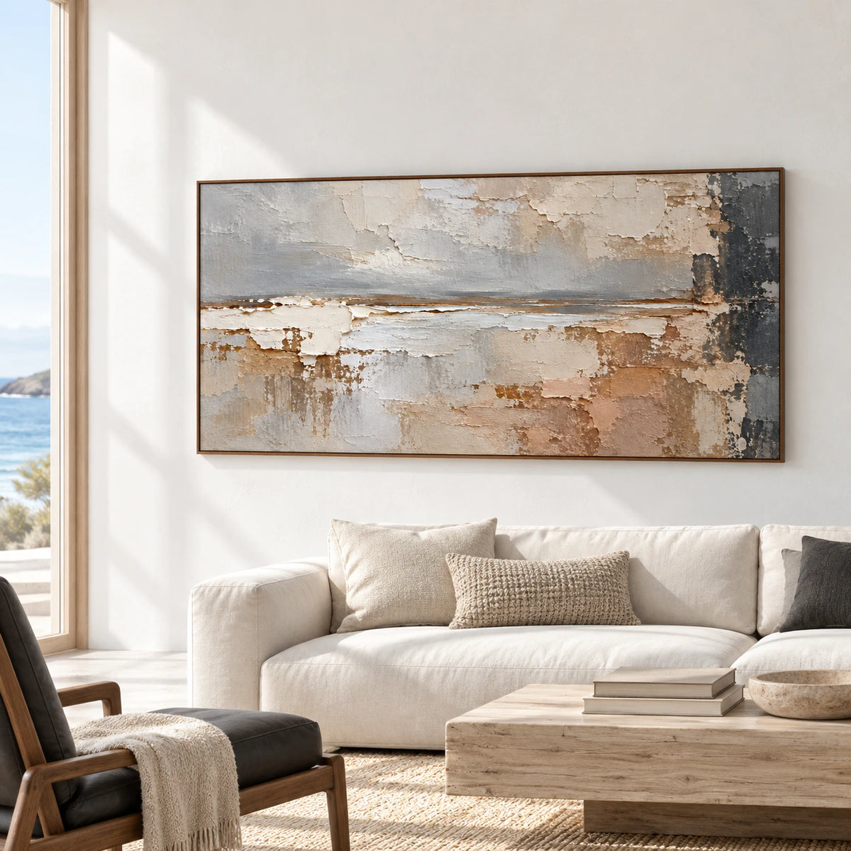 Large horizontal abstract painting in a bright coastal living room with a cream sofa and dark chair, viewed from a distant left oblique angle.