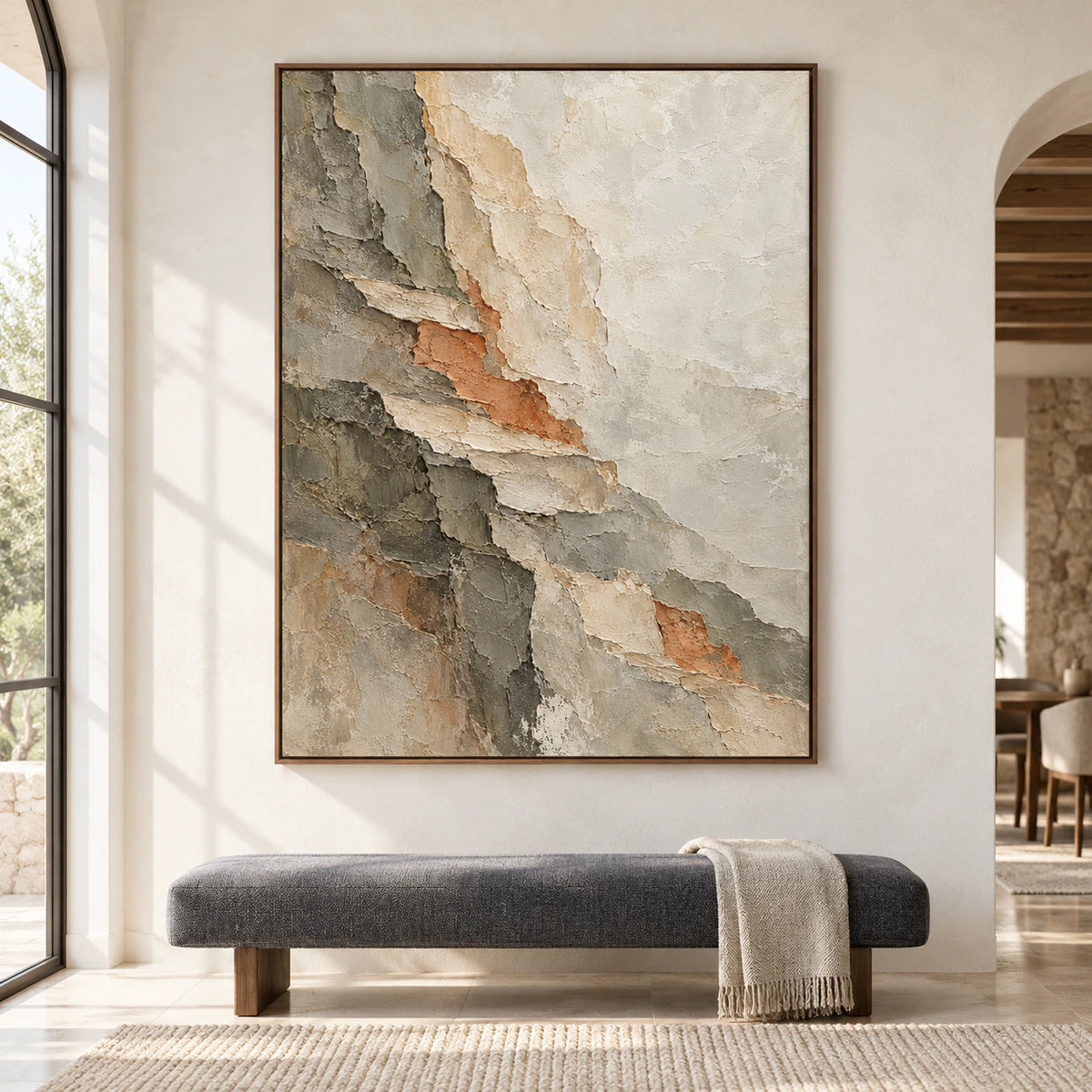 Large vertical abstract painting above an upholstered bench against a pale plaster wall in a spacious, daylit interior, viewed straight on.