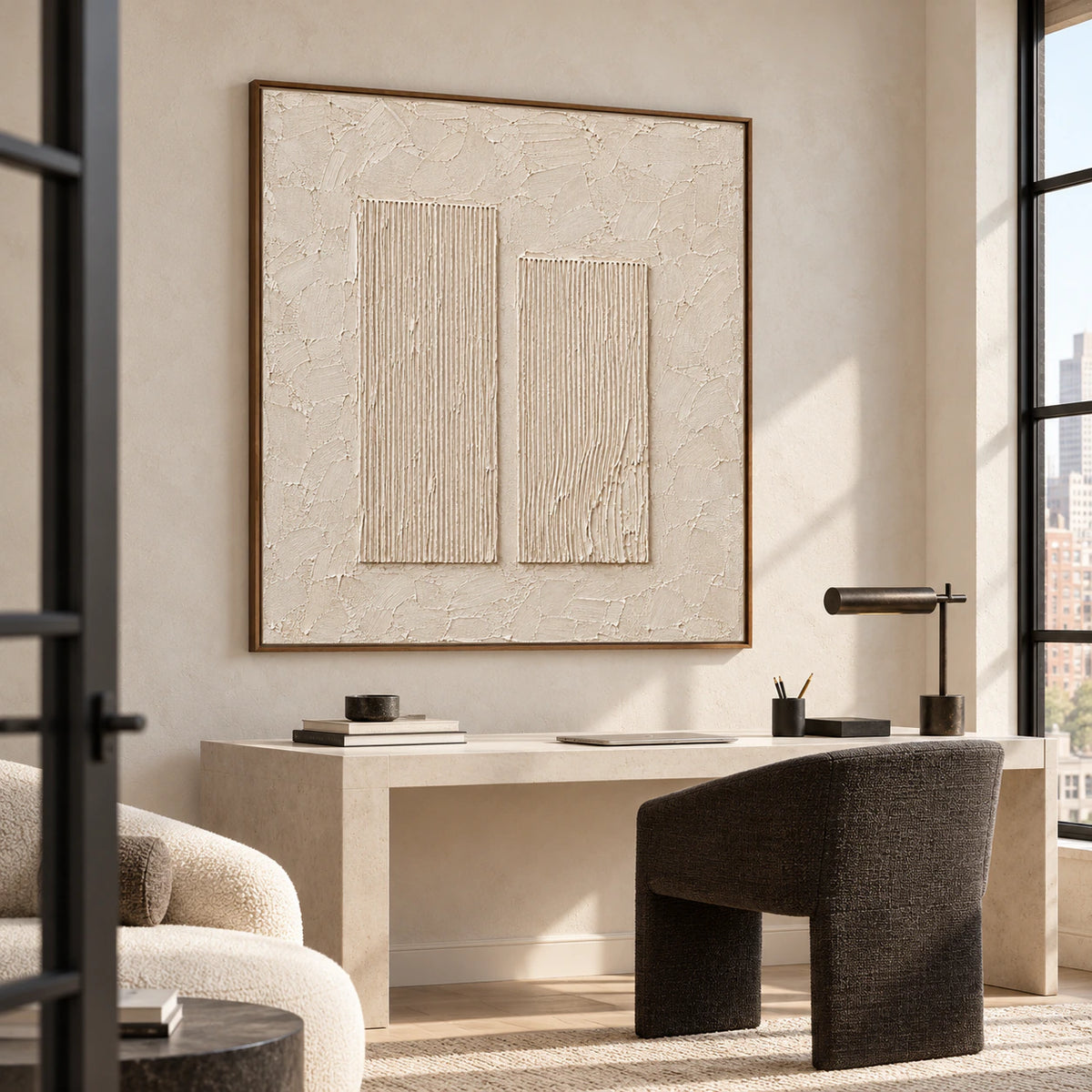 Slightly elevated right oblique view of square ivory artwork above a pale desk with a dark upholstered chair and tall side window.