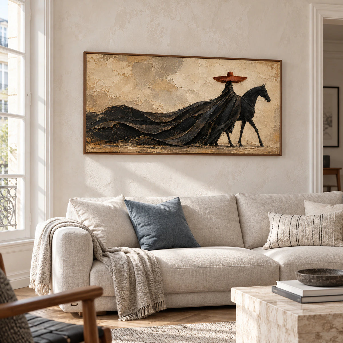 Horse and rider painting above a pale stone-colored sofa in a bright living room with charcoal and ivory accents, viewed from the left.