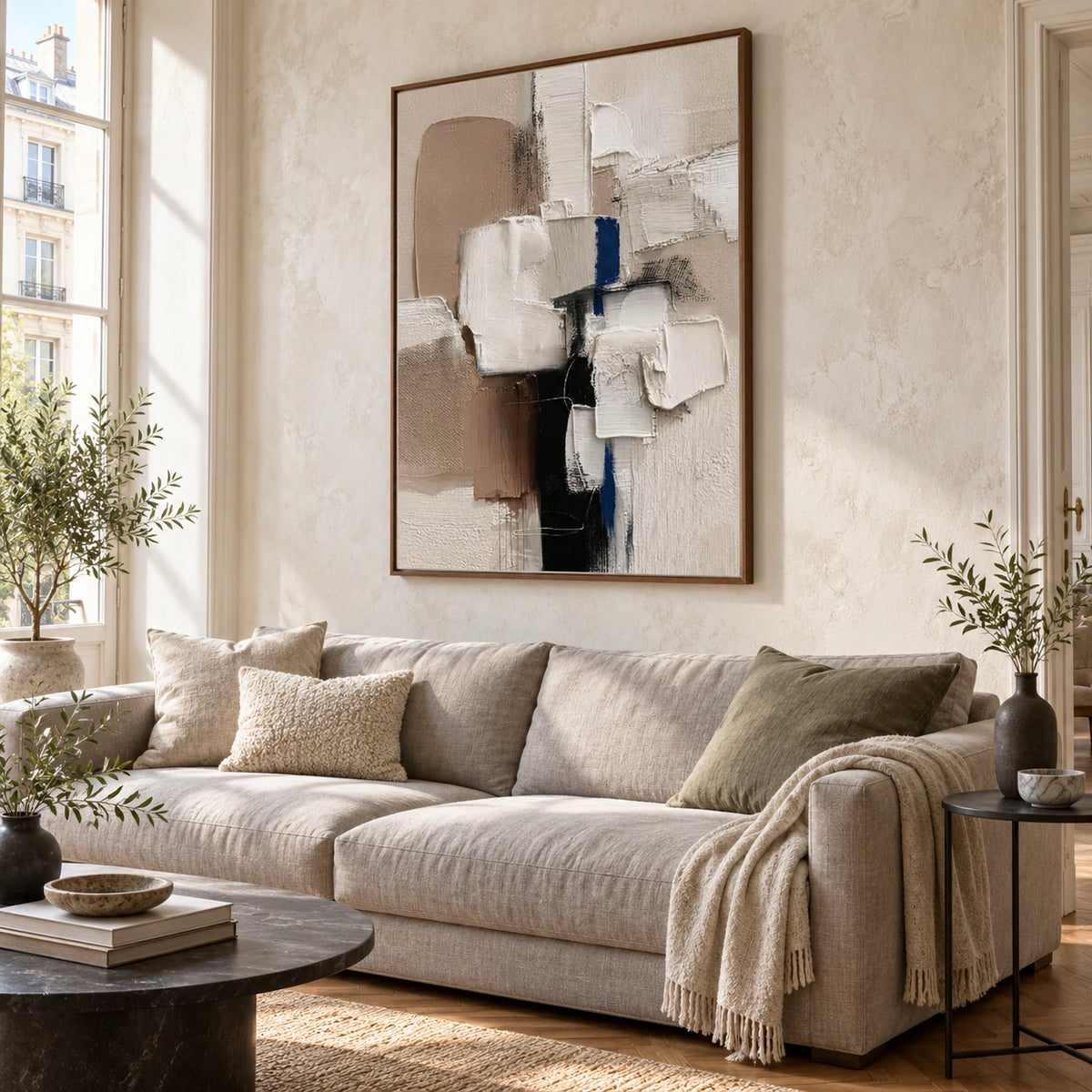 Vertical textured abstract painting above a sculptural sofa in a bright living room.