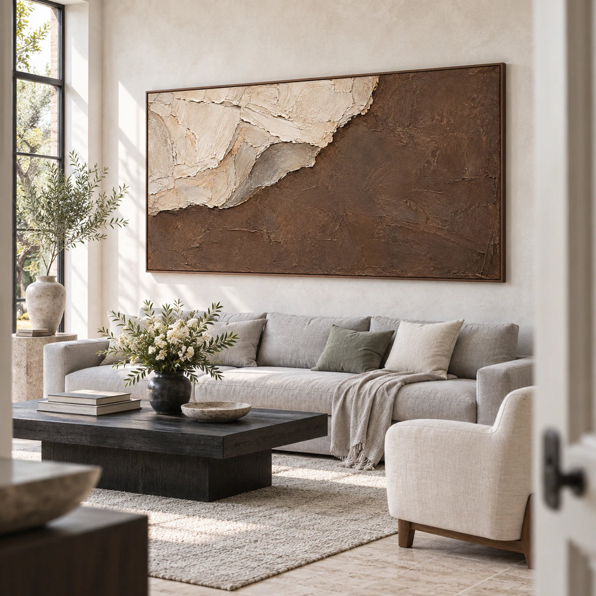 Textured ivory and umber abstract painting above a pale stone living room seating arrangement.