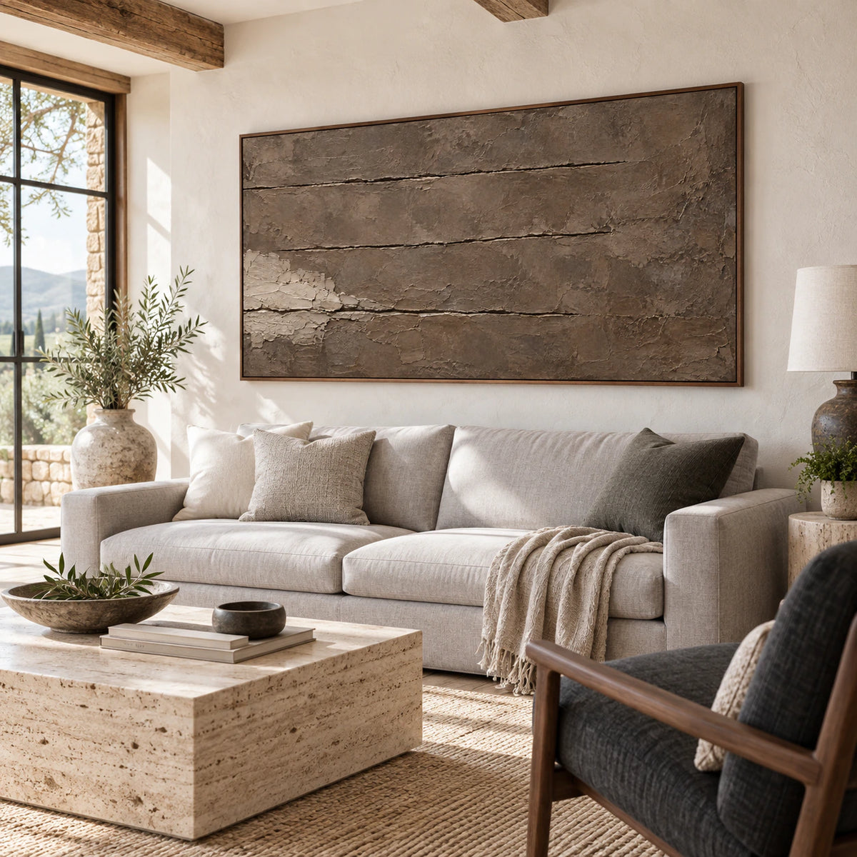 Earth-toned panoramic textured abstract artwork above a restrained sofa in a bright living room.