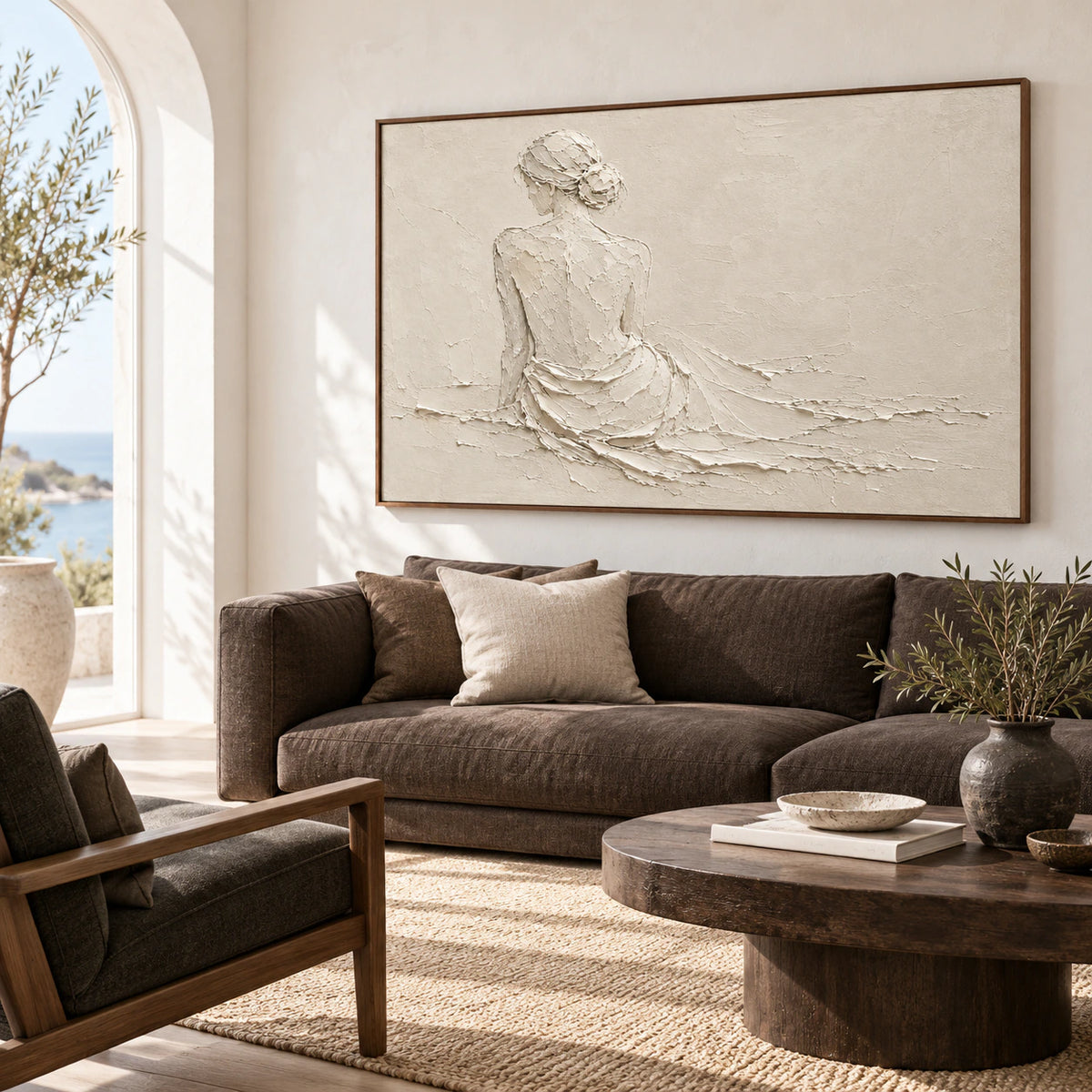Pale ivory seated-figure painting displayed above a restrained low sofa in a bright living room.