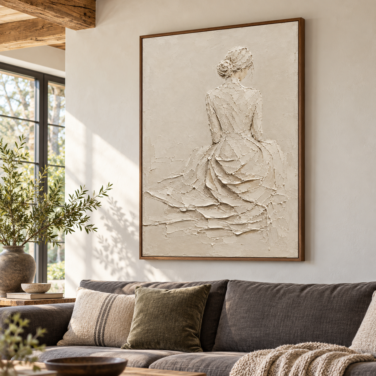 Left oblique view at seated eye level of a large ivory figure painting above a charcoal sofa in a bright living room with pale walls.