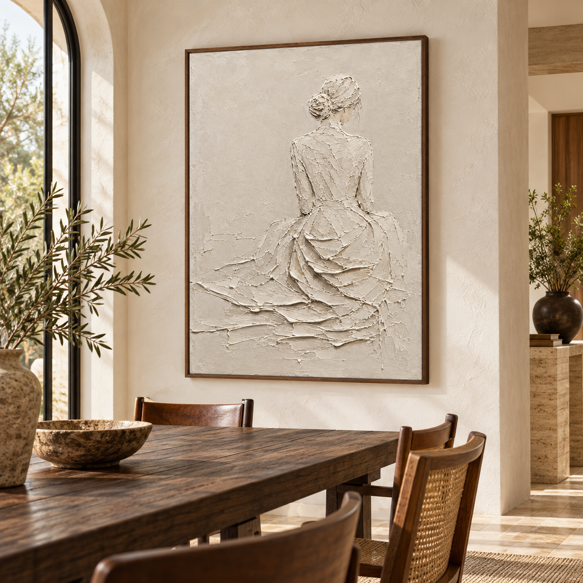 Right oblique view from slightly above table height of an ivory figure painting on a pale plaster wall beside a long dark timber dining table and chairs.