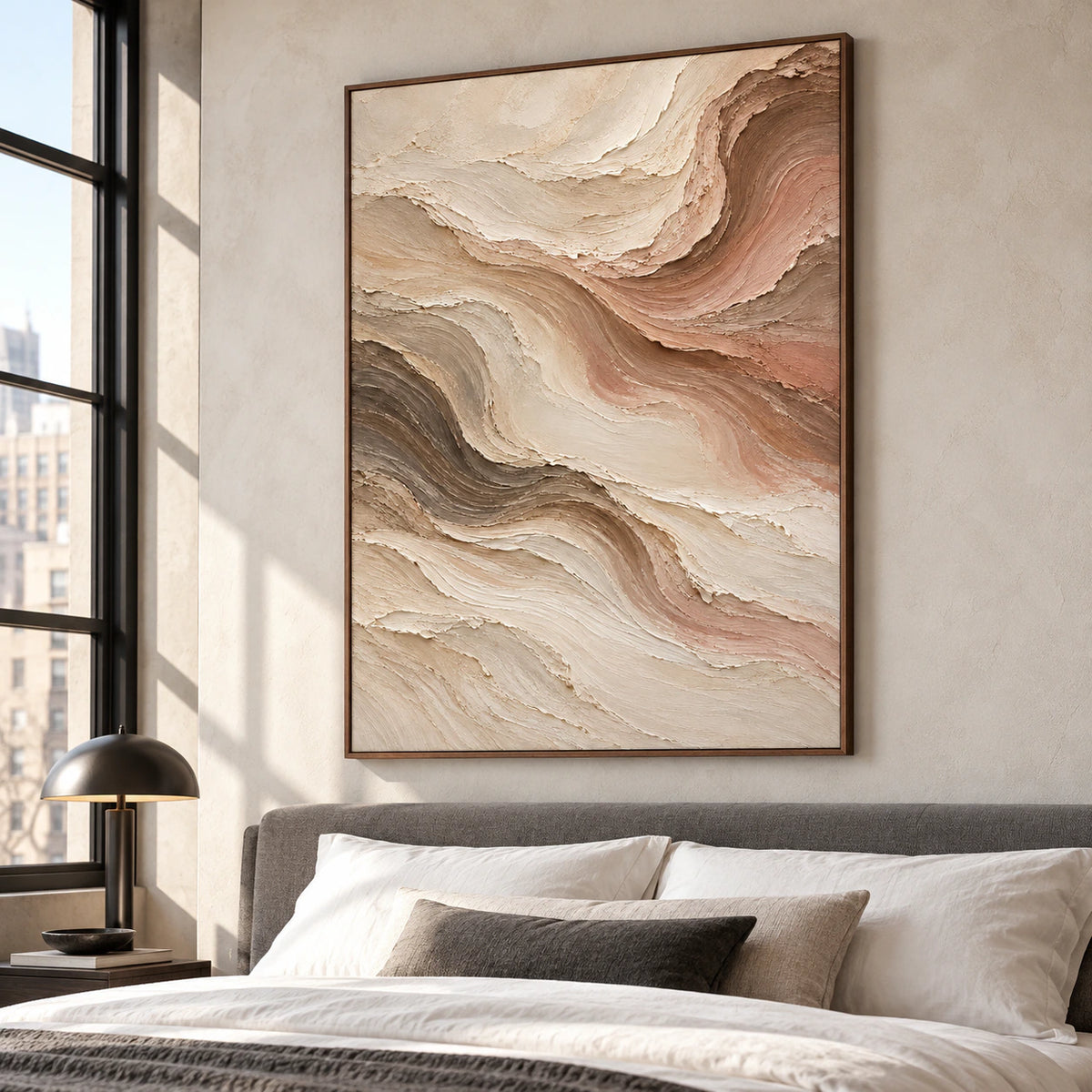 Vertical abstract painting above a bed with white bedding and a slate upholstered headboard, viewed from the left near the foot of the bed in soft daylight.