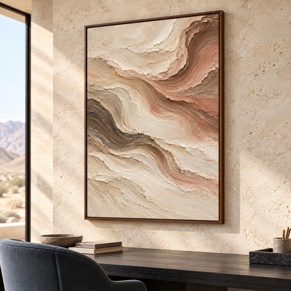 Vertical abstract painting with flowing ivory, taupe, rose and brown bands beside a slim dark wood desk and blue-gray reading chair, viewed from the right in daylight.