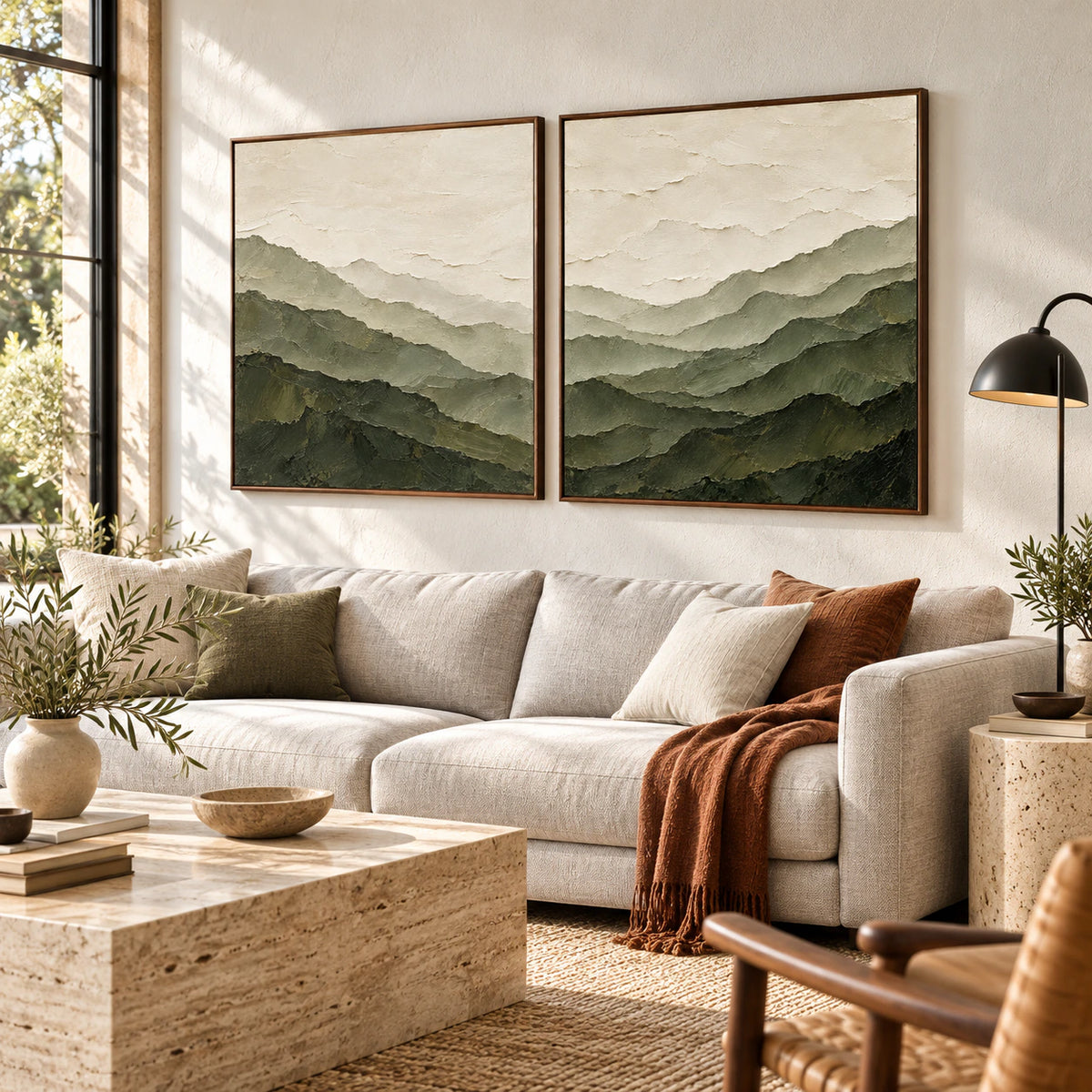 Green mountain diptych in slim walnut frames above a pale sofa in a bright, open living room.