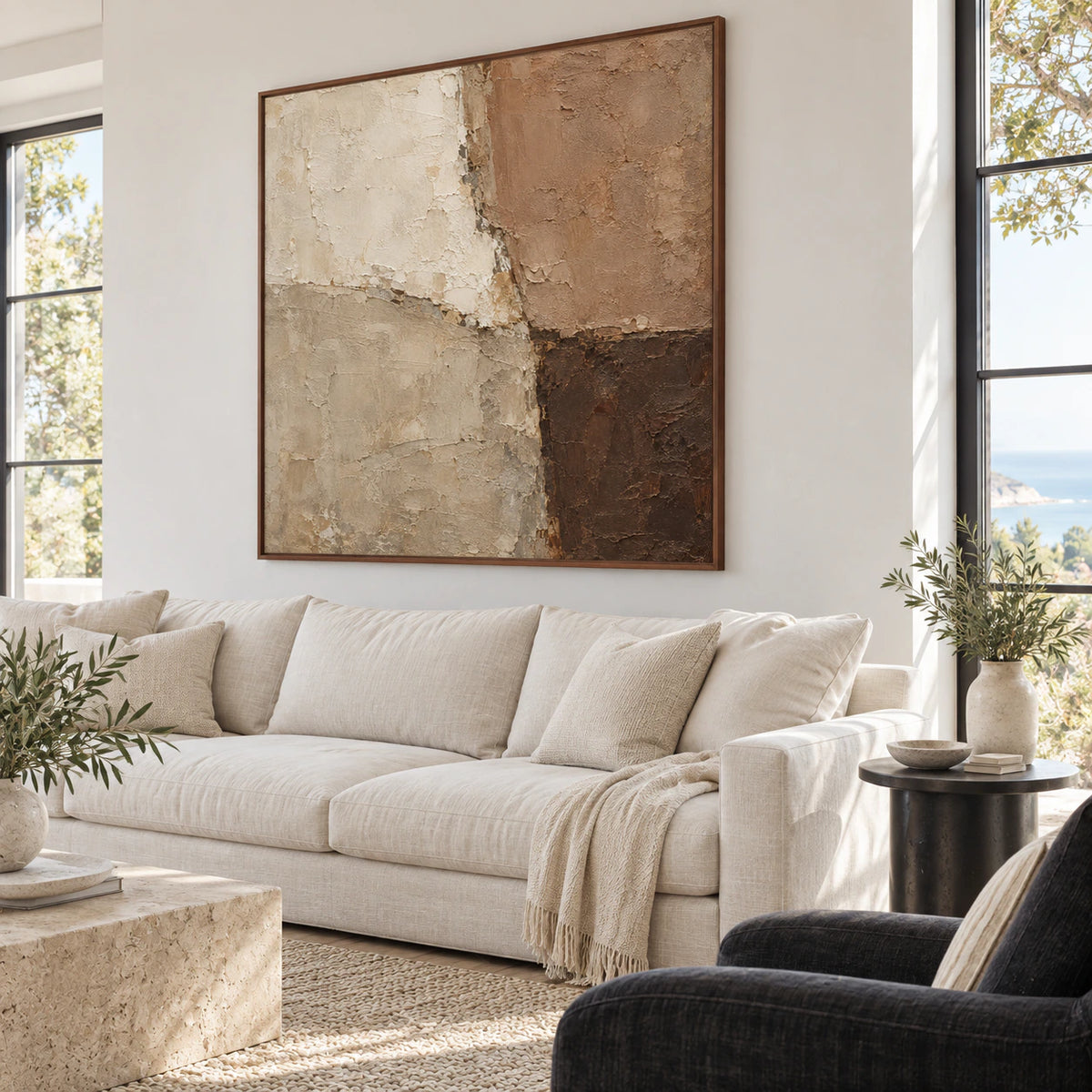 Square textured earth-tone artwork above a restrained sofa in a bright living room.