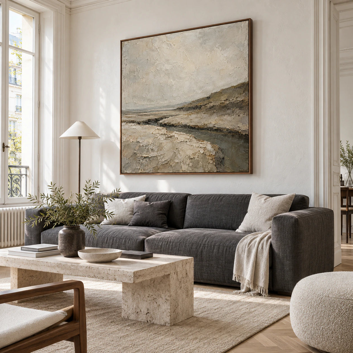 Textured abstract estuary painting above a sofa in a bright, open living room.