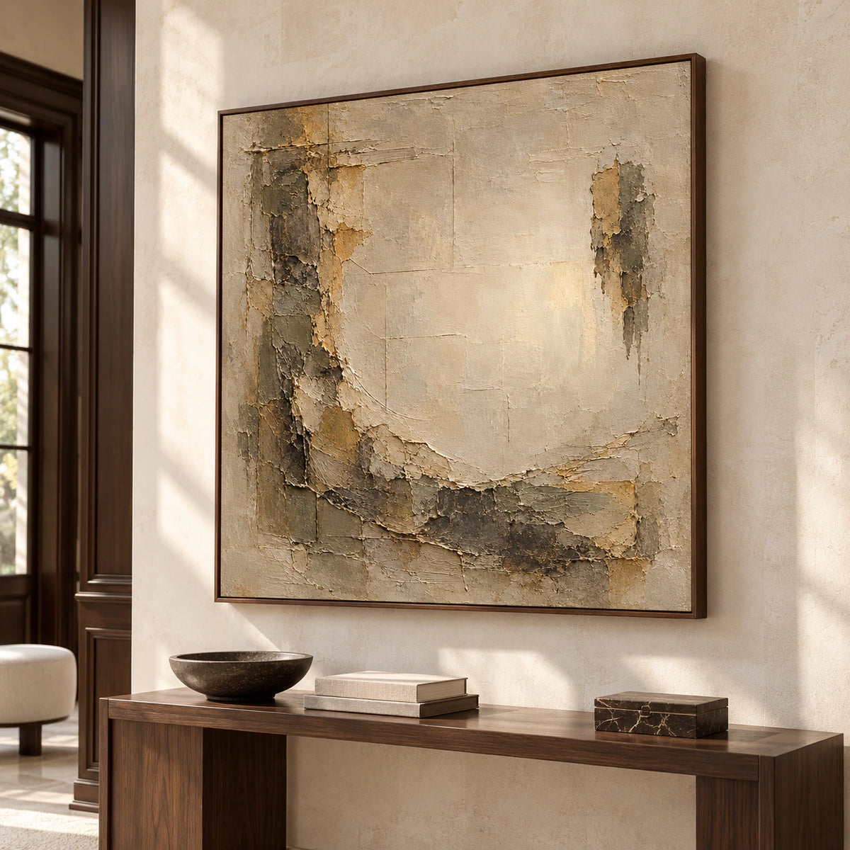 Square abstract painting above a slim dark console against a tall limestone wall in a bright foyer, viewed from a slightly low left angle.